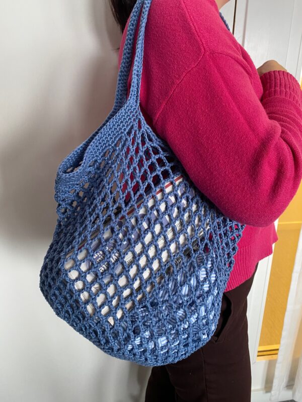 blue crotcheted bag held by person with red hoodie